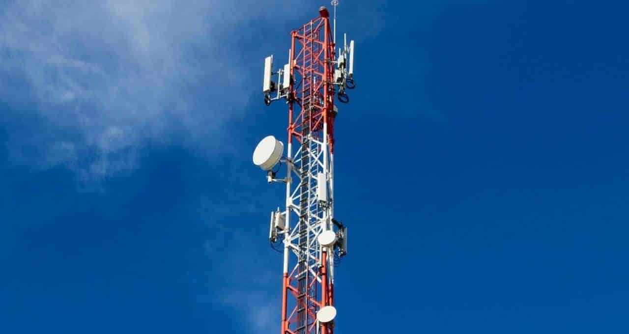 Torre de telecomunicações Tanz em cores vermelho e branco sob céu azul. Infraestrutura robusta com antenas de transmissão, essencial para conectividade e redes móveis.