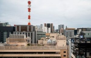 Vista urbana com torre de telecomunicação entre edifícios, representando a atuação da Tanz Engenharia em infraestrutura, reforço estrutural e expansão das redes 5G