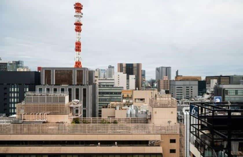Vista urbana com torre de telecomunicação entre edifícios, representando a atuação da Tanz Engenharia em infraestrutura, reforço estrutural e expansão das redes 5G